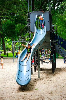 photo of kids playing at a playground on a slide