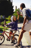 Photo of father giving son on bike a 'high five'.