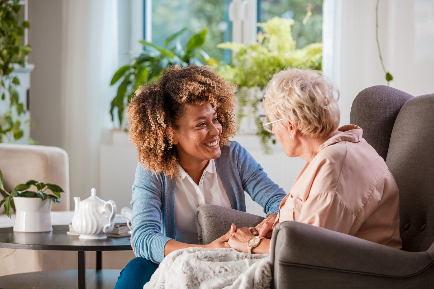 Woman bending down to help care for an elderly woman in a nursing home