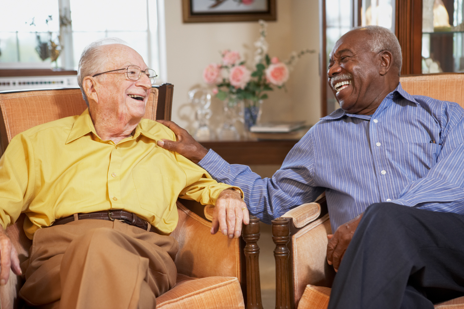 Two older men sitting next to each other in armchairs.