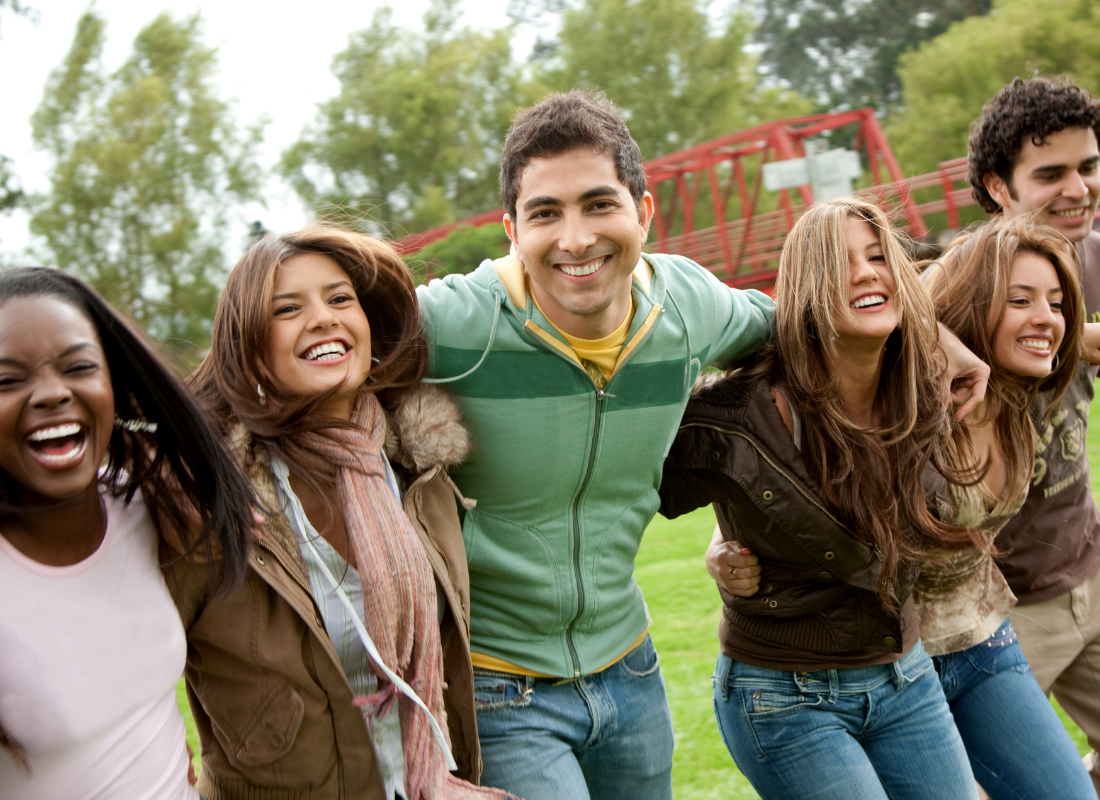 Group of friends hanging out with a man making eye contact with the camera as the main subject.