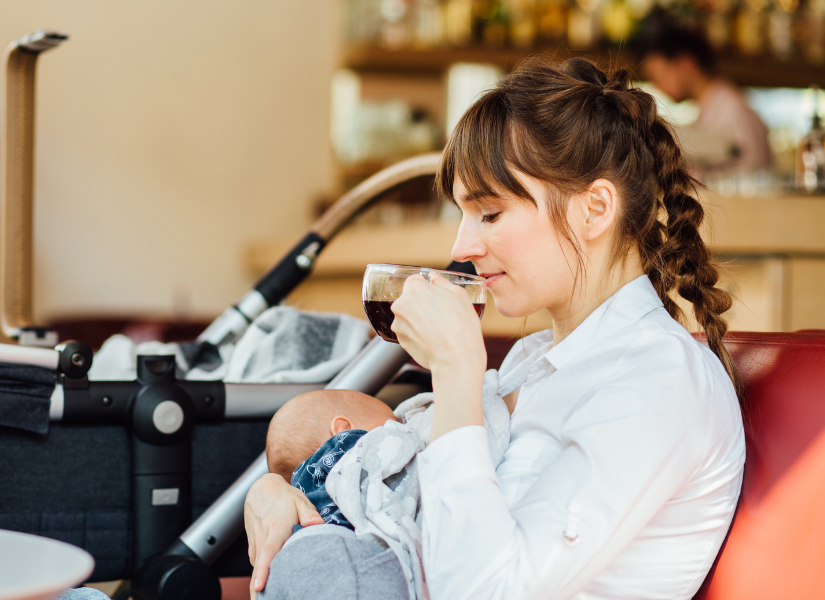 Woman enjoying coffee in a cafe while breastfeeding her baby.