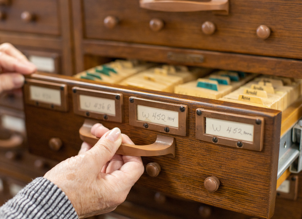 A hand pulling out a drawer of vital records information from 1914.