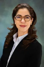 Heidi Miller's headshot. She is wearing a black blazer and round glasses while smiling at the camera.